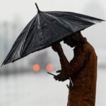 A man makes his way amid rainfall at India Gate in New Delhi