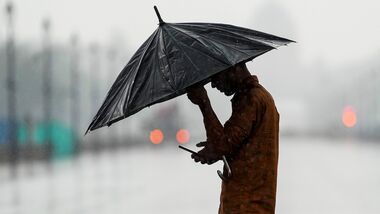 A man makes his way amid rainfall at India Gate in New Delhi