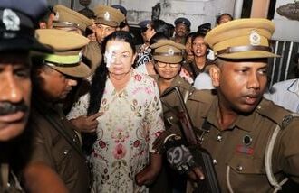 Prison officers escort Shiranthi Rajapaksa, the wife of Sri Lanka's former President Mahinda Rajapaksa, to a prison vehicle outside a magistrate's court in Colombo, Sri Lanka, Wednesday, Oct. 7, 2026. (AP Photo/Lahiru Harshana)