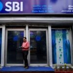 A man checks his mobile phones in front of a State Bank of India (SBI) branch in Kolkata, India