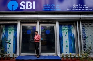 A man checks his mobile phones in front of a State Bank of India (SBI) branch in Kolkata, India