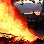 A fire is seen with the Eiffel Tower in the background during a demonstration to protest against the ‘high cost of living’, in Paris on October 17, 2026.