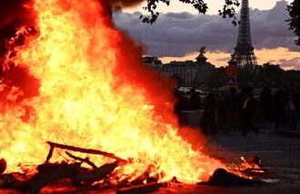 A fire is seen with the Eiffel Tower in the background during a demonstration to protest against the ‘high cost of living’, in Paris on October 17, 2026.