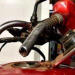A pump attendant fuels a motorcycle at a petrol station