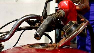 A pump attendant fuels a motorcycle at a petrol station