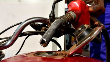 A pump attendant fuels a motorcycle at a petrol station